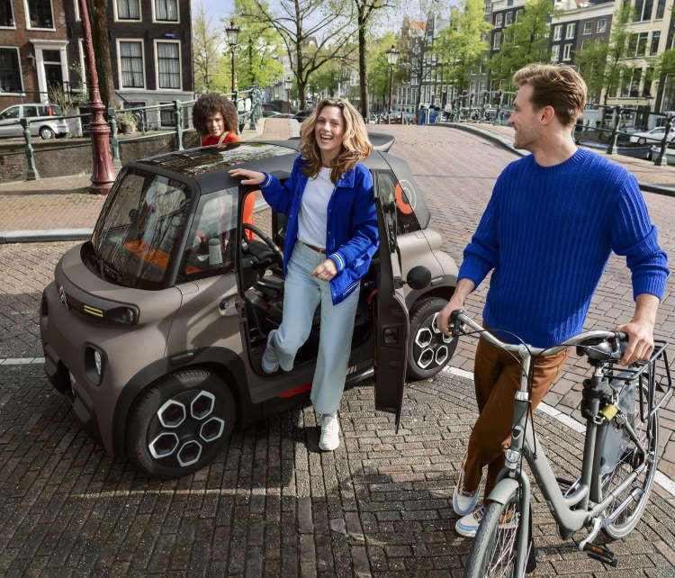 Дівчина виходить з-за керма Citroën Ami на вулиці